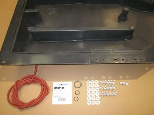 Kondensatsammler von Remeha, bestehend aus einem schwarzen Behälter und diversen Zubehörteilen wie einer roten Leitung, Schrauben, Unterlegscheiben und Dichtungen.